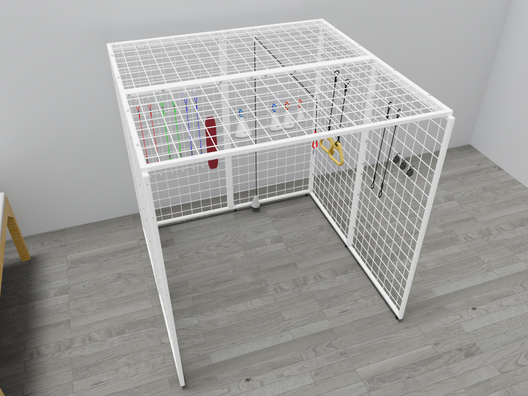 Angled view of the Summit Sensory Gym Universal Exercise Unit, featuring a sturdy white metal grid structure. Inside the cage are therapy tools, including colorful resistance bands, a red padded support, white cone-shaped accessories with hooks, and yellow handles attached to ropes. The cage is positioned on a light gray wood-style floor in a bright, minimalistic therapy setting with part of a wooden table visible in the corner.